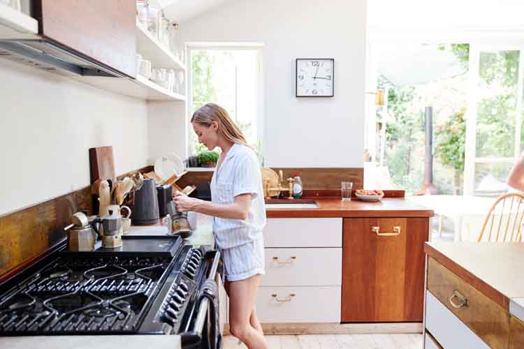 Image of woman making breakfast in beautiful modern kitchen featuring solid surface, granite, and engineered stone countertops by Earnest Watkins Construction professional commercial and residential remodeling in Panama City, Florida